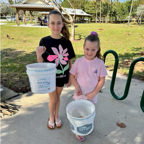 two girls holding buckets for a beach clean up